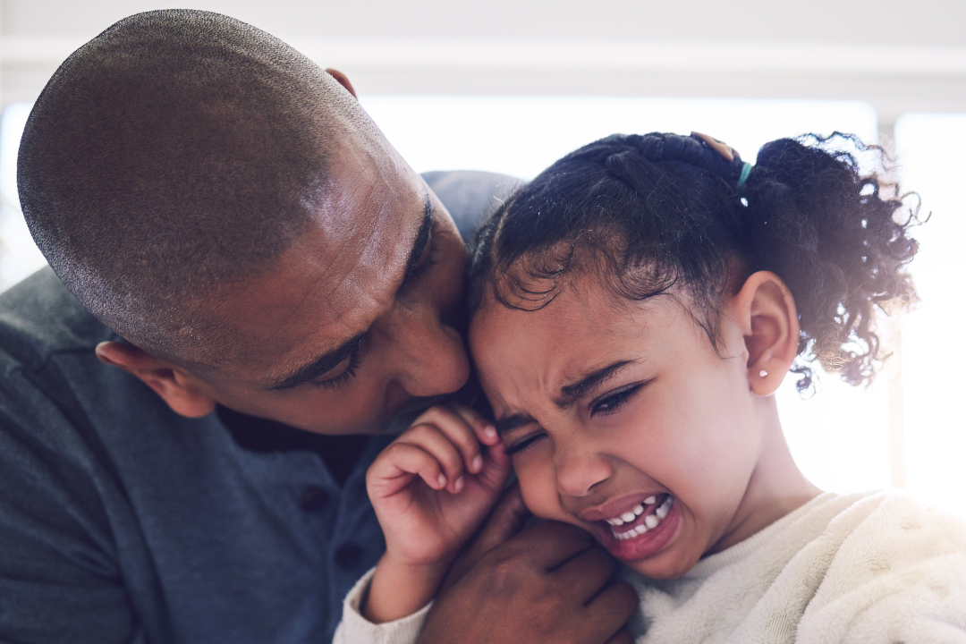 A father gently comforting his distressed child, offering a warm embrace and listening attentively to their concerns, creating a safe and supportive environment.