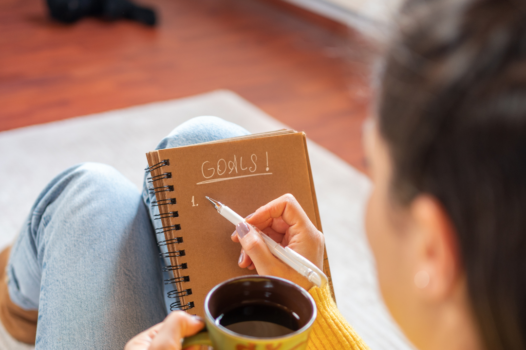 A journal open on a desk, surrounded by a pen and coffee cup, symbolizing reflection and planning for New Year's resolutions.